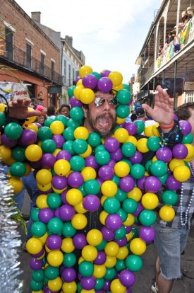 Gonzo Mardi Gras reveler covered in a dense array of purple, green and gold balls