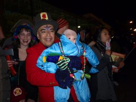Bundled-up for cold weather, including toddler in one-piece ski outfit, at 2010 Krewe du Vieux parade