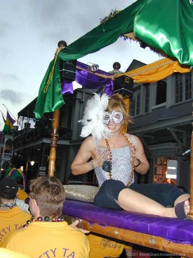 A smiling female masker riding the Titty Taxi, a deluxe palanquin, on Fat Tuesday 2001