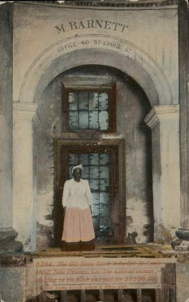 Postcard showing African-American woman standing in front of old slave block at St. Louis Hotel