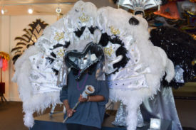 Visitor to the Mardi Gras Museum of Costumes and Culture dressed in a costume and holding a scepter